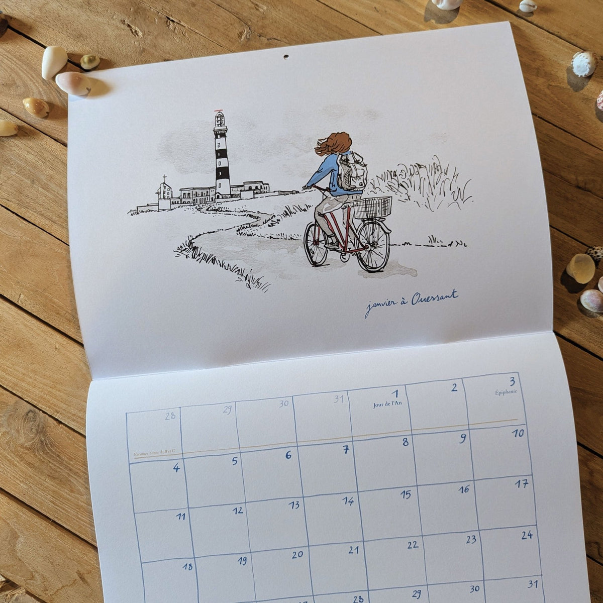 Calendrier 2027 « D'île en île » ouvert : cycliste près d'un phare rayé noir et blanc