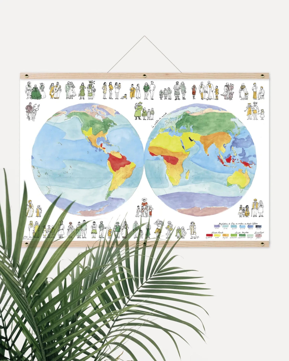 Affiche Palette du monde suspendue par un support en bois, derrière une plante verte